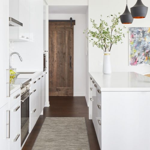 corktown condo renovation - wood floors - barn door custom millwork - white kitchen with waterfall white quartz counter - bright artwork - linda mazur design full service canadian designer