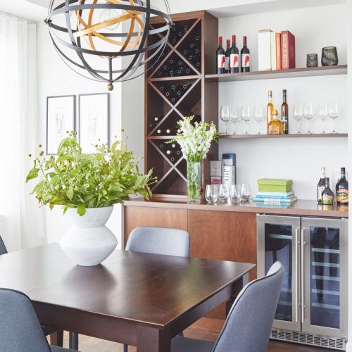 toronto condo in corktown - custom millwork bar area with bar fridge - dining room wood table with blue upholstered dining chairs - dining room chandelier - small space storage - toronto designer linda mazur design