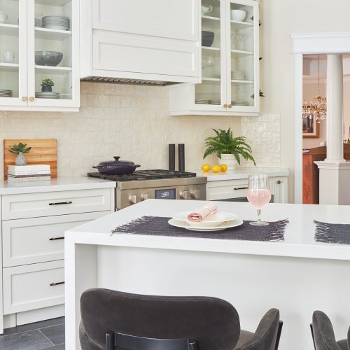 markham luxury family kitchen renovation - cream white custom millwork cabinets and range hood with glass cabinets - white quartz waterfall countertops black porcelain flooring - velvet counter stools CB2 - design build renovate linda mazur design toronto canada designer