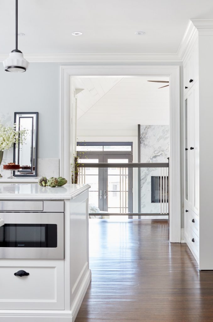 historic toronto homes - luxury family home renovations - white and black kitchen - custom kitchen millwork - quartz countertops - wood flooring - glass railing - kitchen overlooking sunken sunroom - marble fireplace - vaulted ceiling - linda mazur design toronto designer