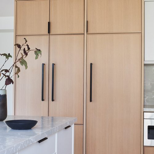 toronto condo kitchen renovation scandi, black barstool vignette, quartz counter tops, natural wood cabinets, two colour cabinets, white cabinets, custom kitchen, herringbone floors, toronto designer, built-in fridge, panelled fridge and pantry linda mazur design